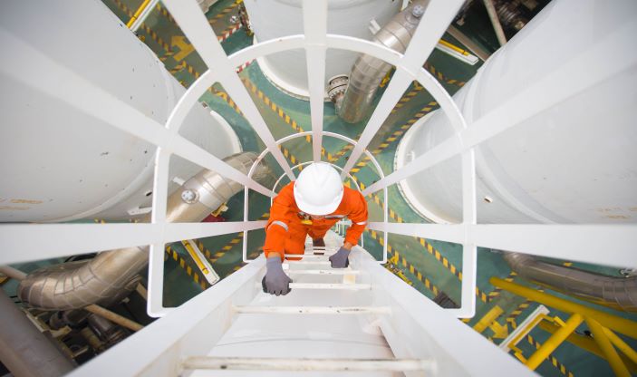 Foto: Shutterstock.com Mann med hjelm klatrer i metallstige.